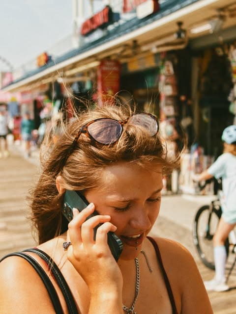 Dziewczyna rozmawiająca przez telefon na słonecznym deptaku
