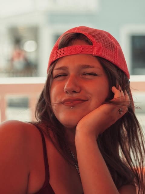 Portret uśmiechniętej dziewczyny w czerwonej czapce z daszkiem